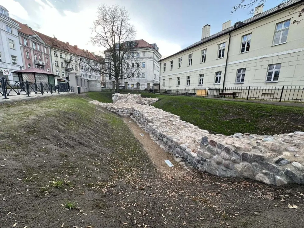 Makieta Zamku Kazimierzowskiego z brązu na tle odsłoniętych murów